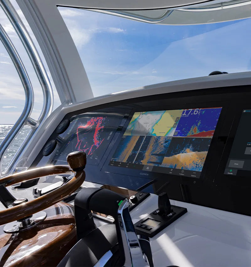 Modern yacht helm with Garmin marine chartplotter, navigation displays, and wood steering wheel
